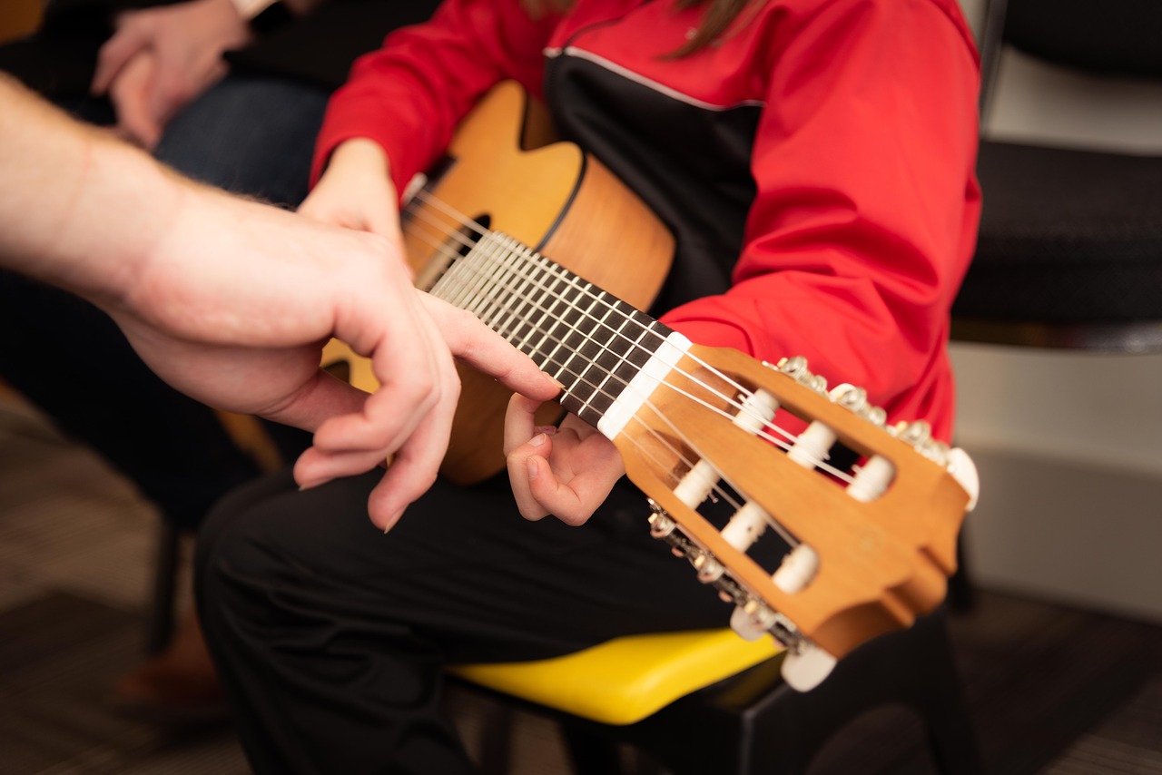 Opettaja opettaa lasta soittamaan kitaraa